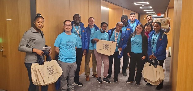 a large of group staff at the hallway, some of them are holding a batch of grocery bags.