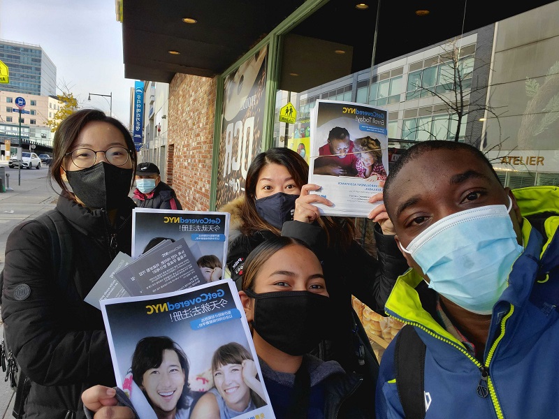 Get Covered NYC Specialists wearing face masks and canvassing on the street. They are holding up Get Covered NYC flyers written in simplified Chinese.