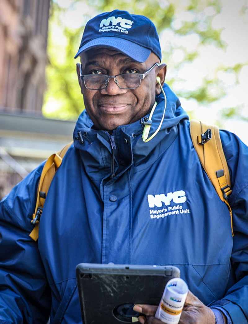 Man wearing blue colored PEU hat and jacket holding informational flyers