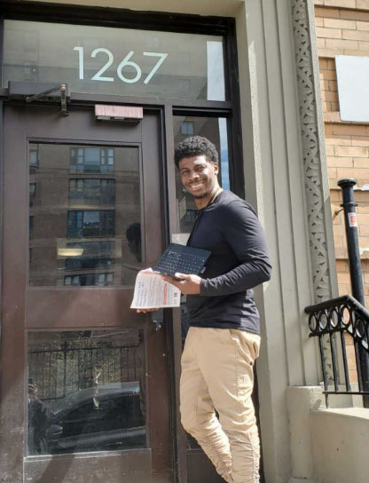 A man is holding a laptop while standing in front of a door
