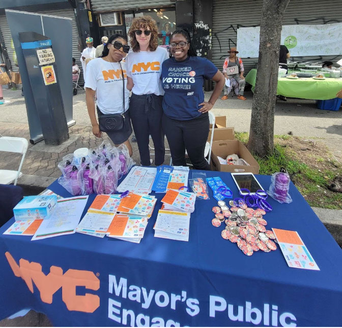A group of three women representing Mayor Public Engagement Unit smiling as their photoes being taken.