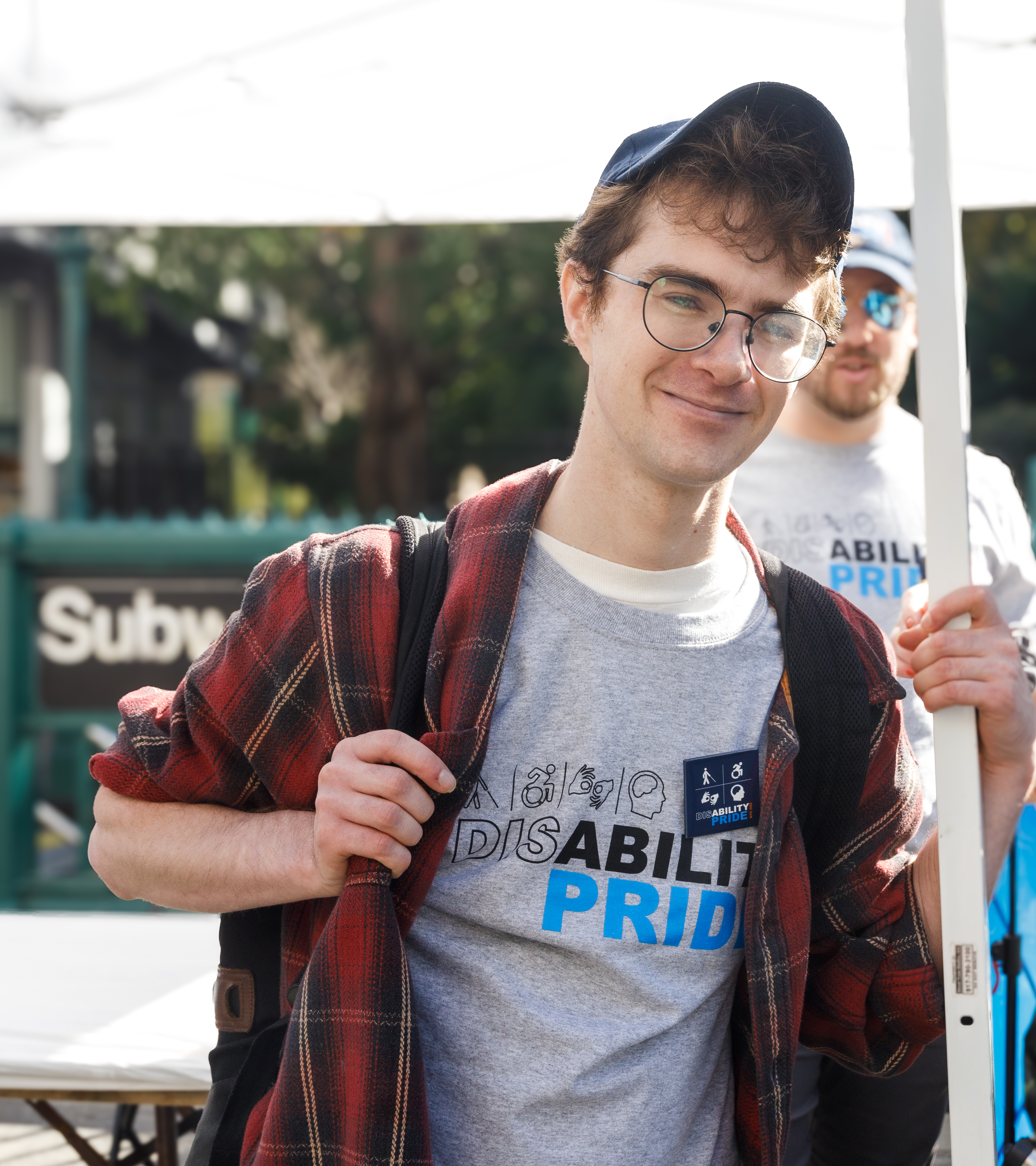 Will, smiling and wearing a Disability Pride shirt.