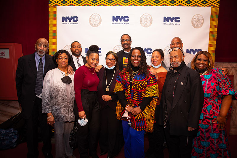 Eleven guests pose for a picture in front of a step & repeat.