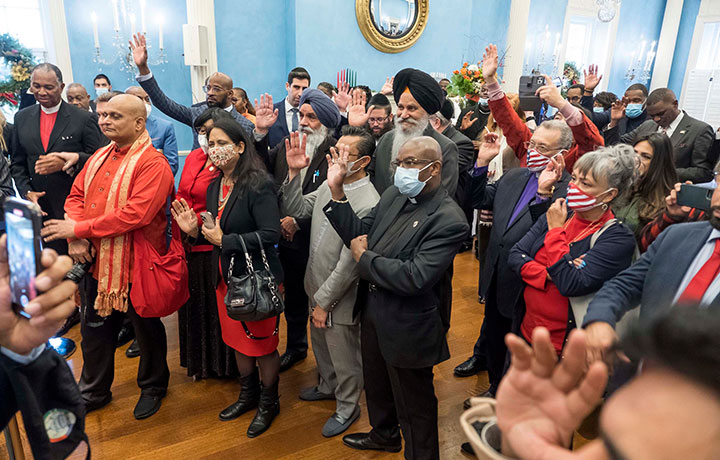 Guests in the ballroom at Gracie Mansion with their hands raised in response
                                           