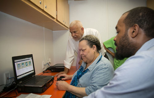 GM Michael Kelly helps an elderly female resident with her online recertification inside one of NYCHA's Digital Vans