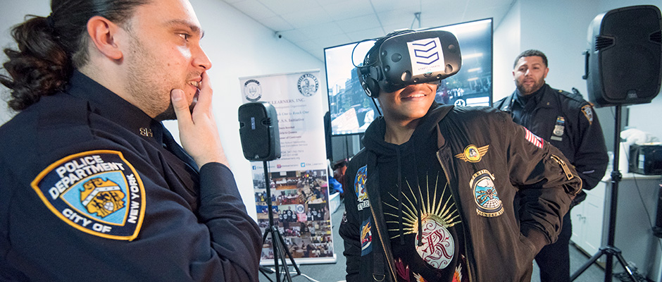 Smiling teenager wearing a VR headset, two amused cops look on
