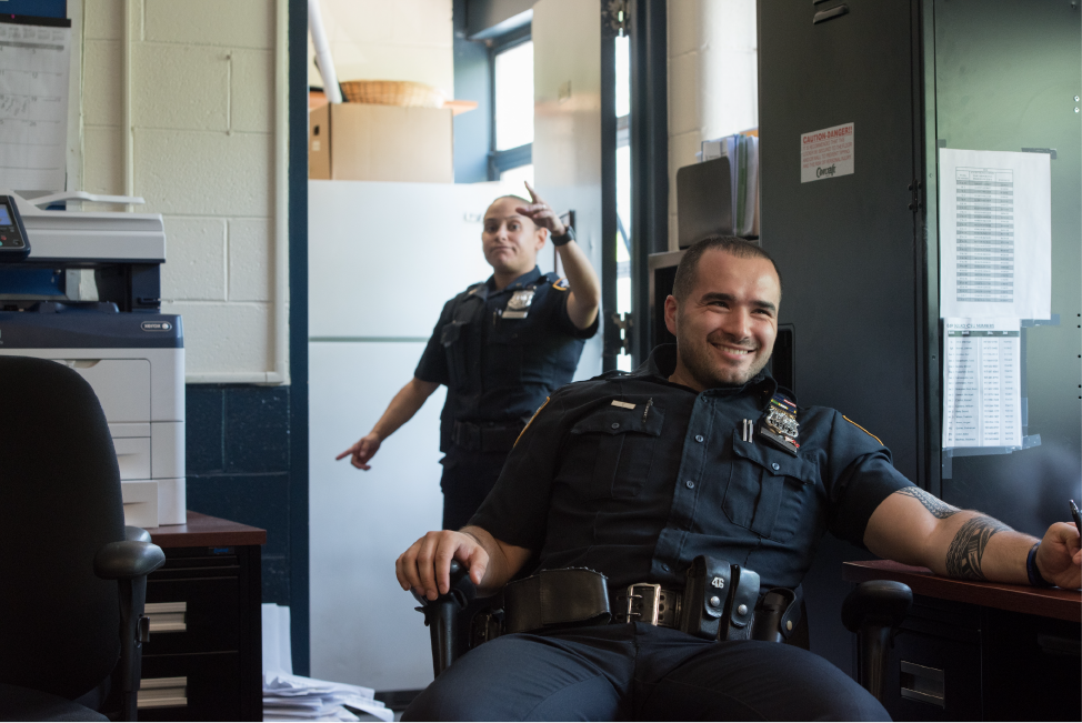 Sanchez and Mujaj at desks in the precinct
