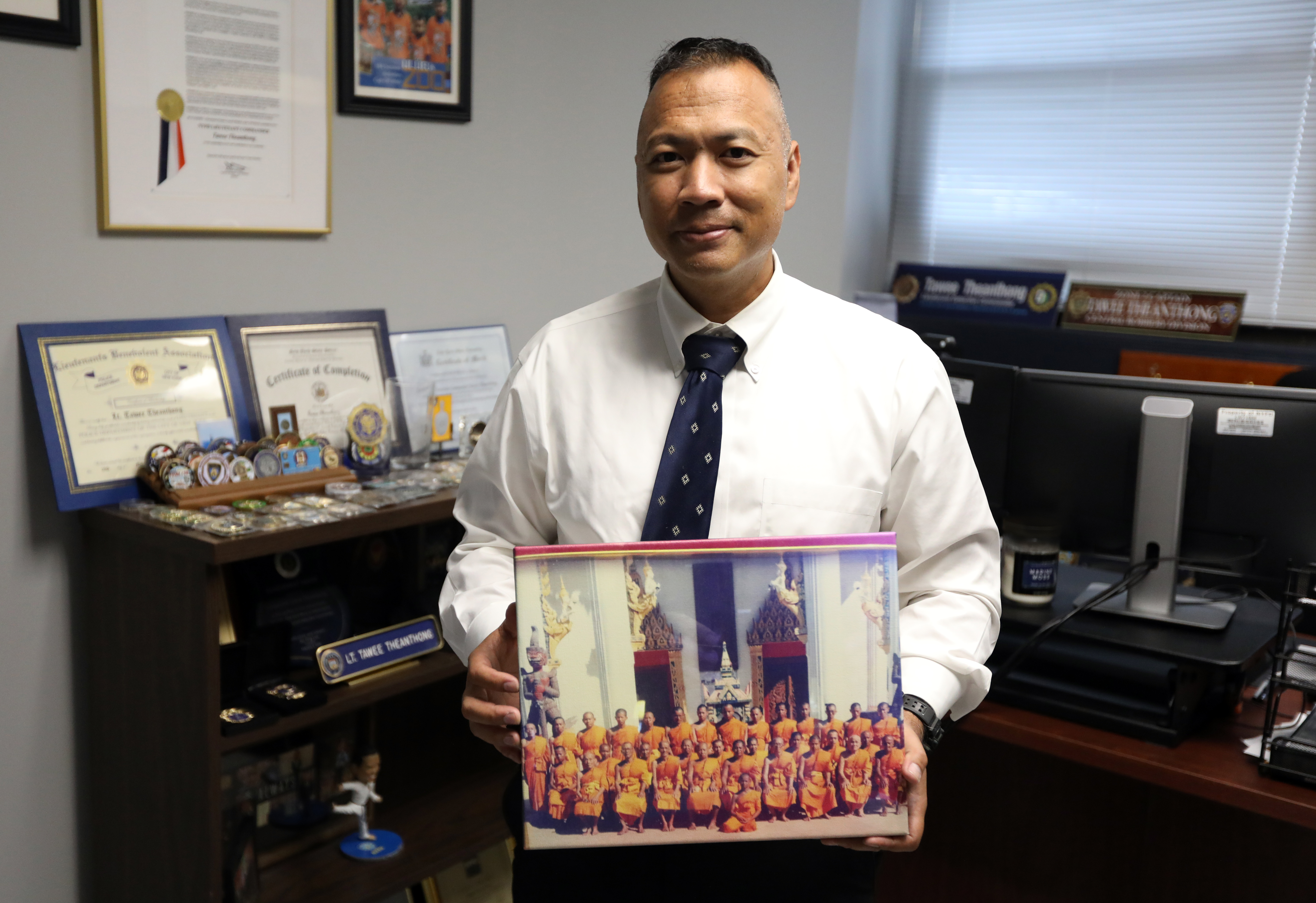 Captain Theanthong holding a photo from his days of being a monk