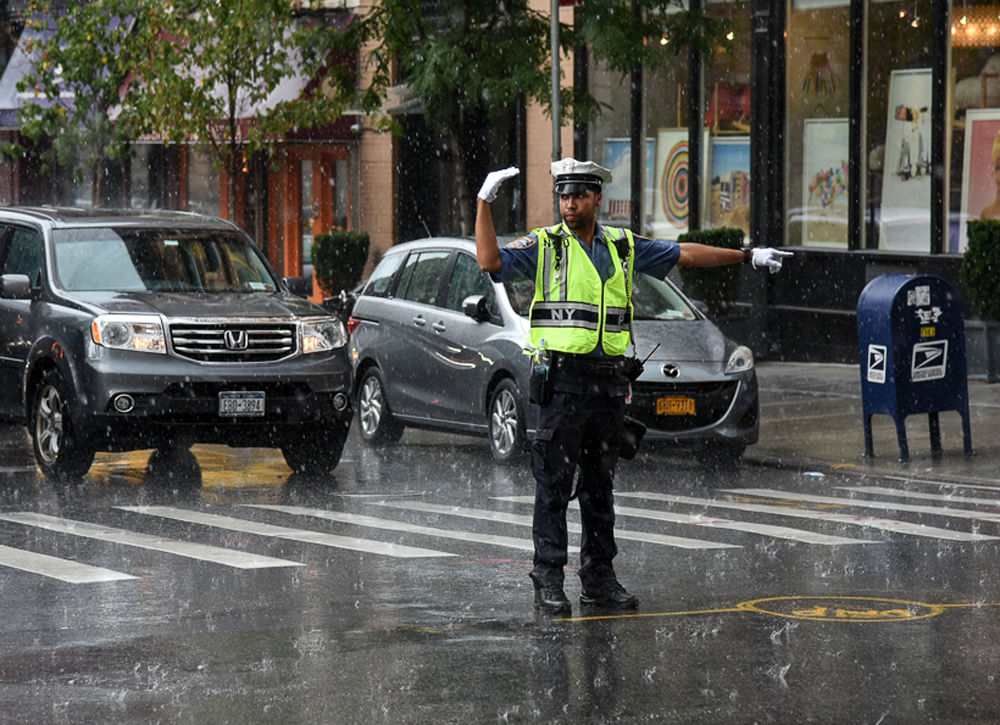An unexpected rain storm doesn't stop an NYPD Traffic Enforcement Agent from directing traffic