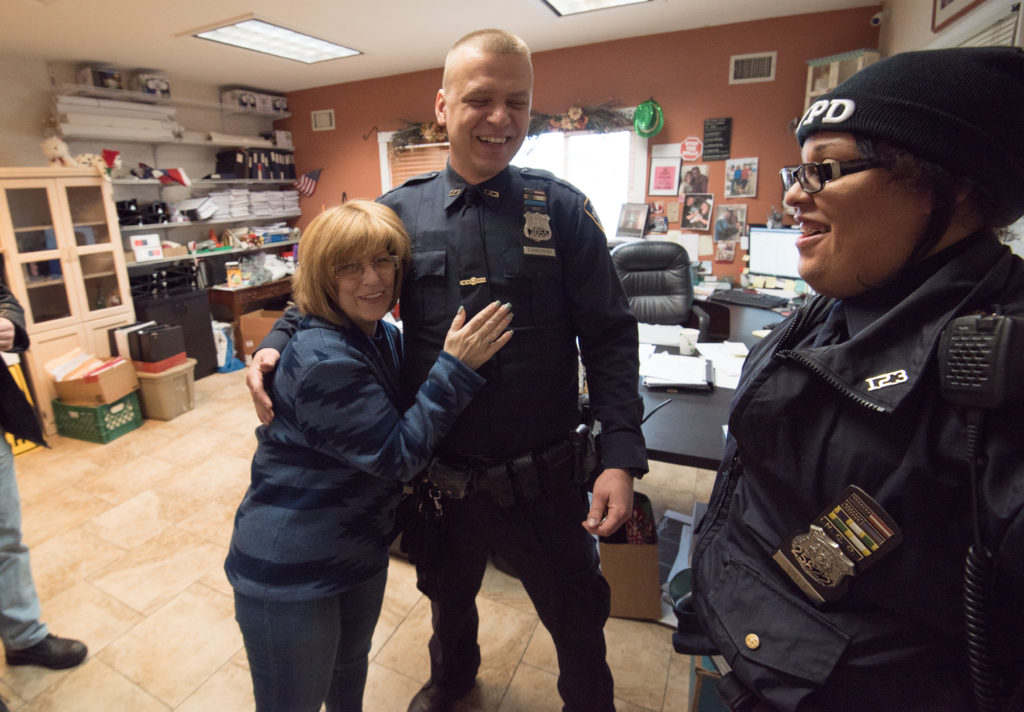 Woman hugging one police officer, another police officer standing near and smiling