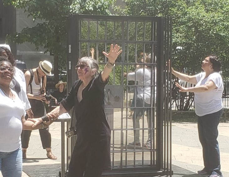 A group of people circling an outdoor public artwork called Wall of Silence. Wall of Silence a public artwork in Collect Pond Park, in lower Manhattan that brings awareness to criminalized domestic and gender-based survivors. 