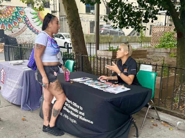 An E N D G B V staff member speaking to a community member at a National Night out Event in the Bronx.