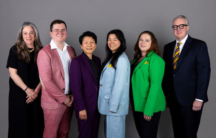 group of people standing in front of gray background
                                           