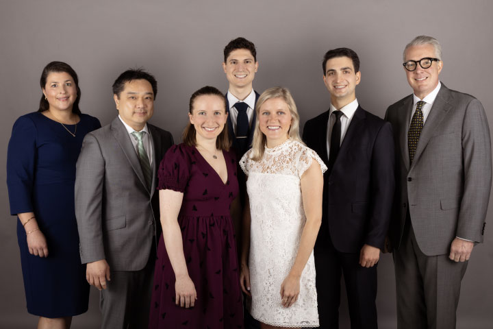 group of people standing in front of gray background
                                           