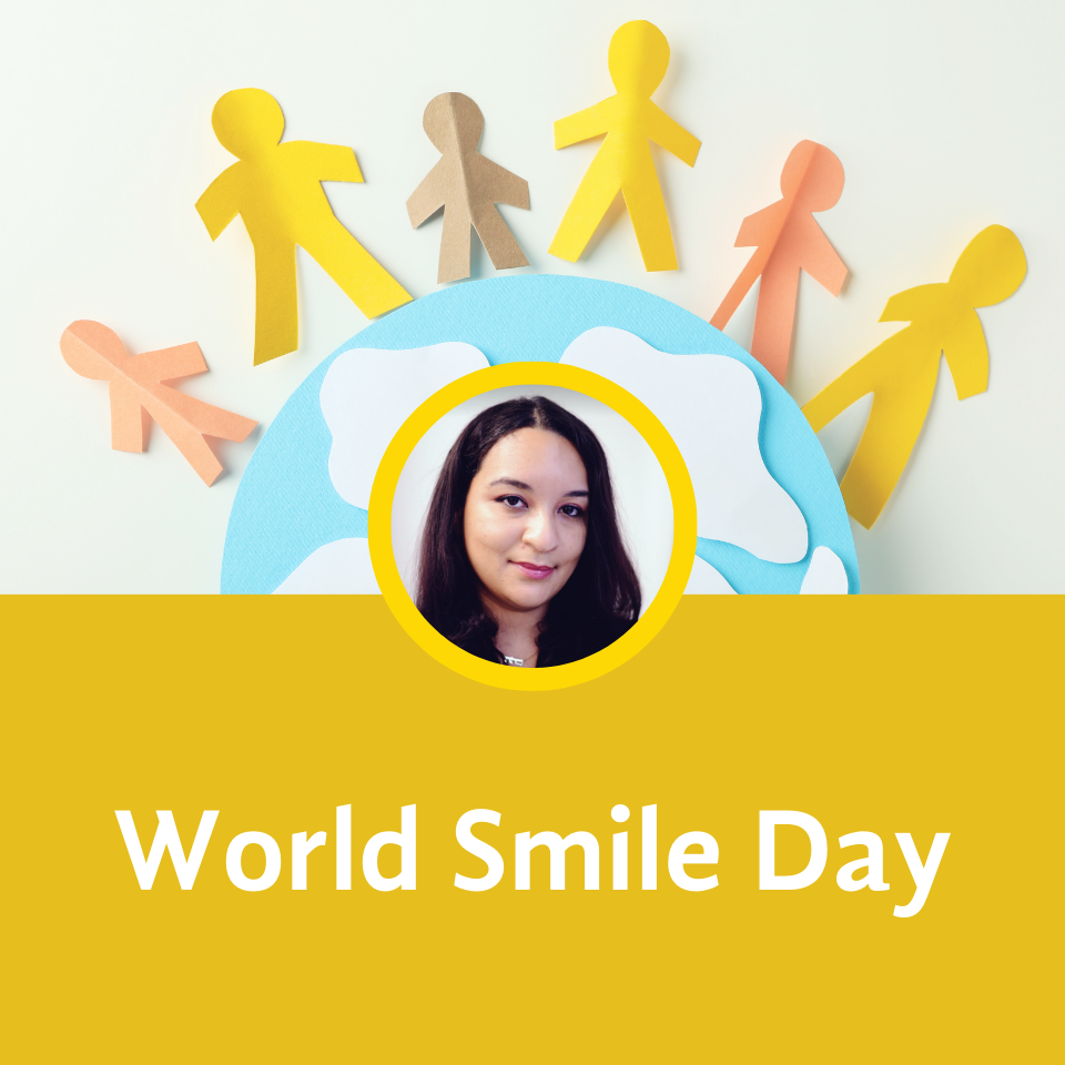 Photo of a person smiling.  There are paper cut-outs in the shape of people holding hands