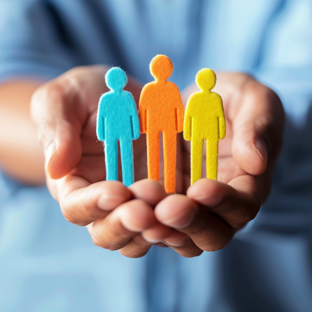 Hands in a cupping position holding paper cutouts of 3 people
