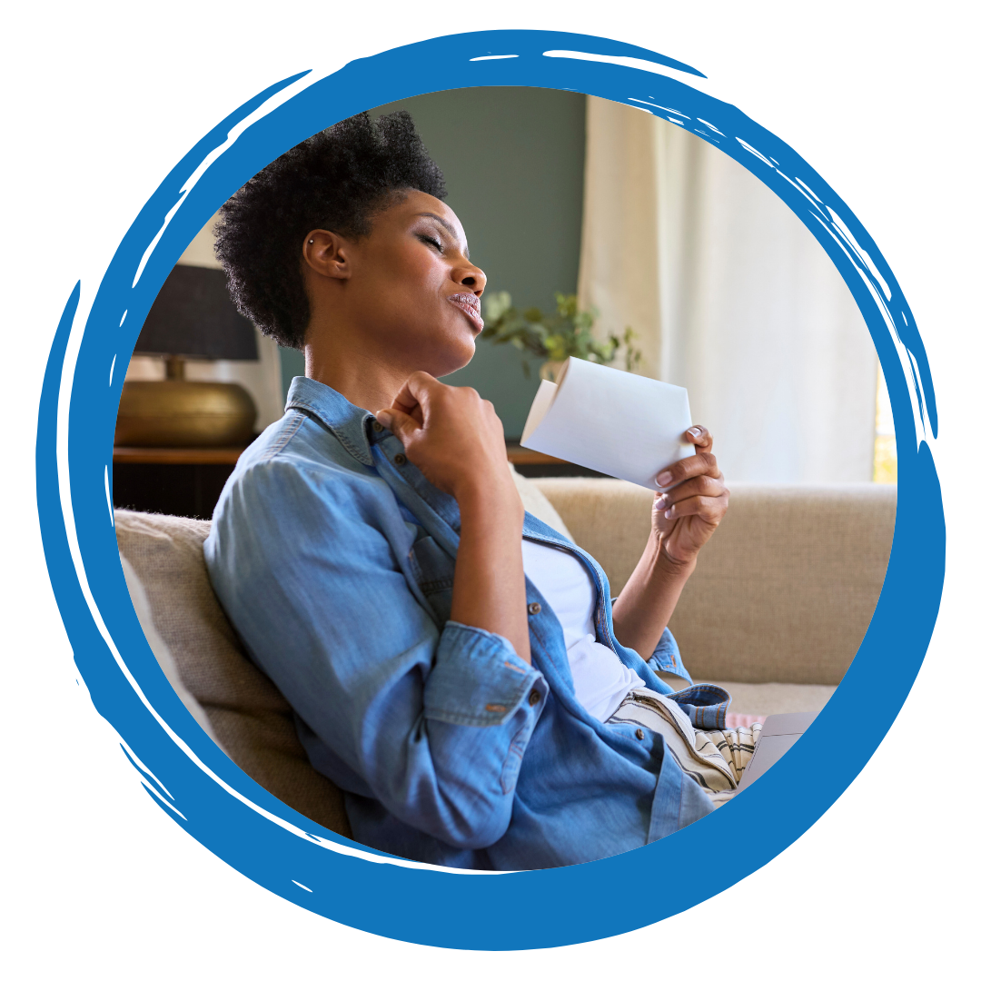 Person sitting on a couch fanning themselves with a piece of paper