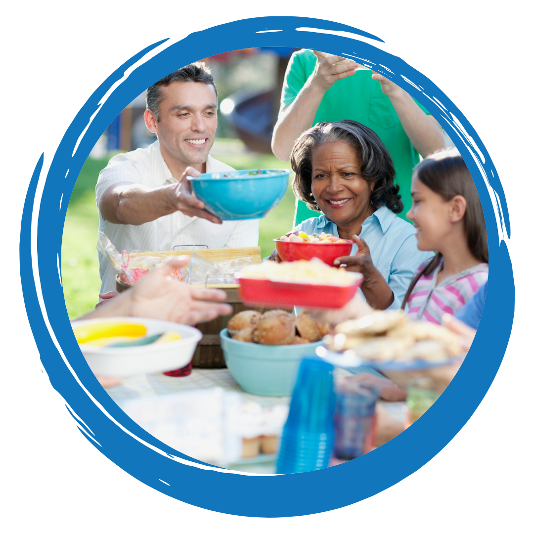 People passing food at a table, having an outdoor celebration