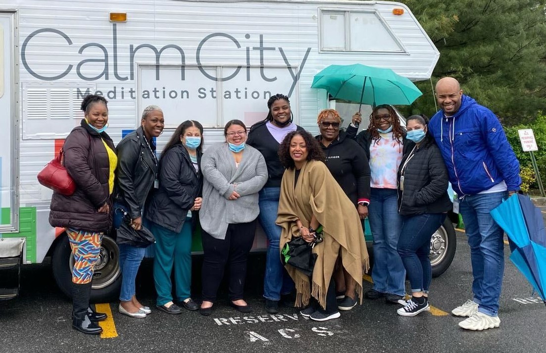 Group of people smiling in front of mobile meditation vehicle