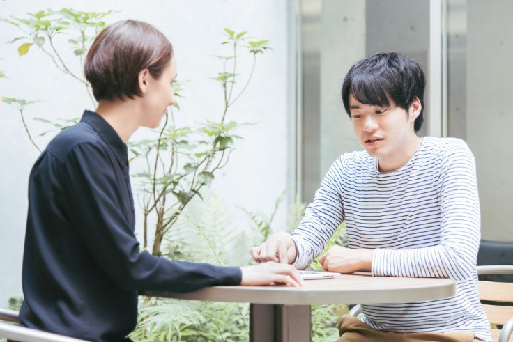 Two Friends Sitting and talking Outside at a Table