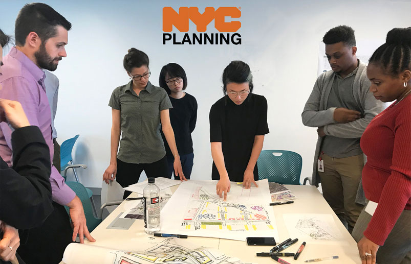 People gathered around a table in an office talking and looking at a map.