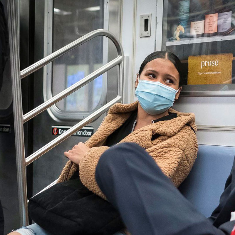 Woman with a face covering seated on the subway