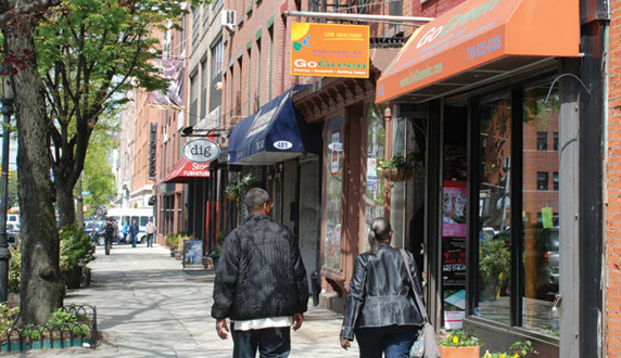 Streetscape with storefronts and people crossing a crosswalk