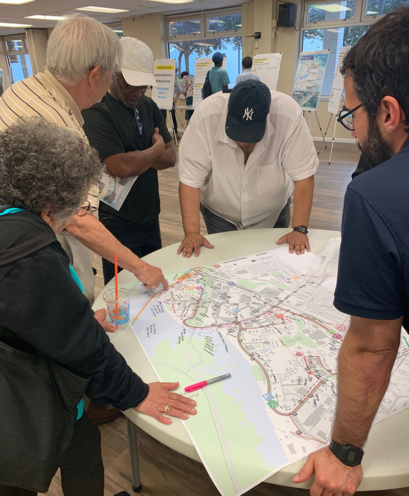 Planning staff speak with Co-Op City residents using a map to mark up likely routes to and from the Metro-North station area. 