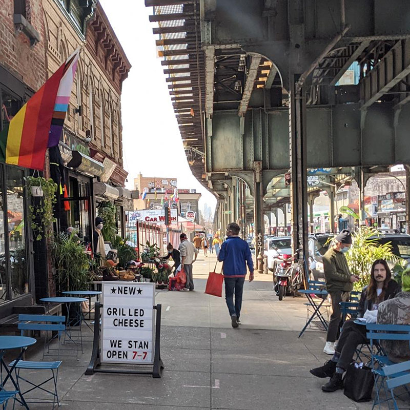Sidewalk with outdoor seating under elevated train tracks 