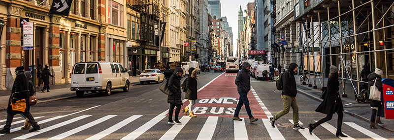 Streetscape with storefronts and people crossing a crosswalk