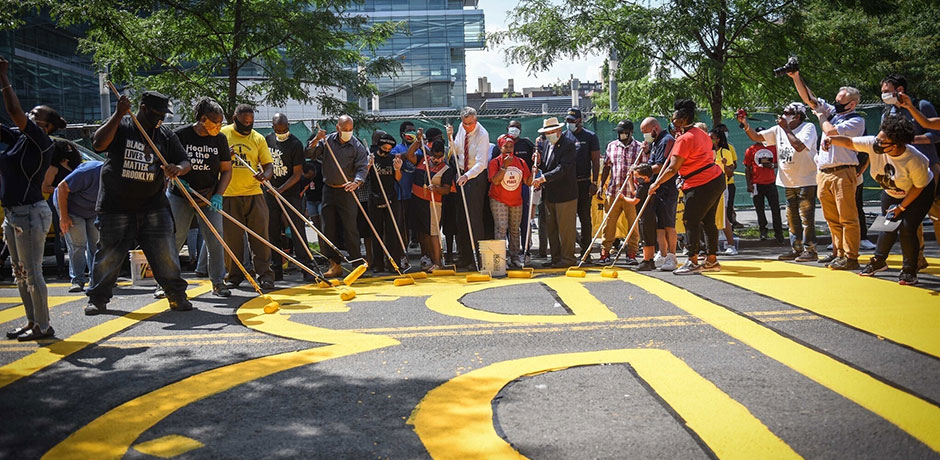 Photo of Mayor de Blasio and a group of people painting a ground mural
                                           