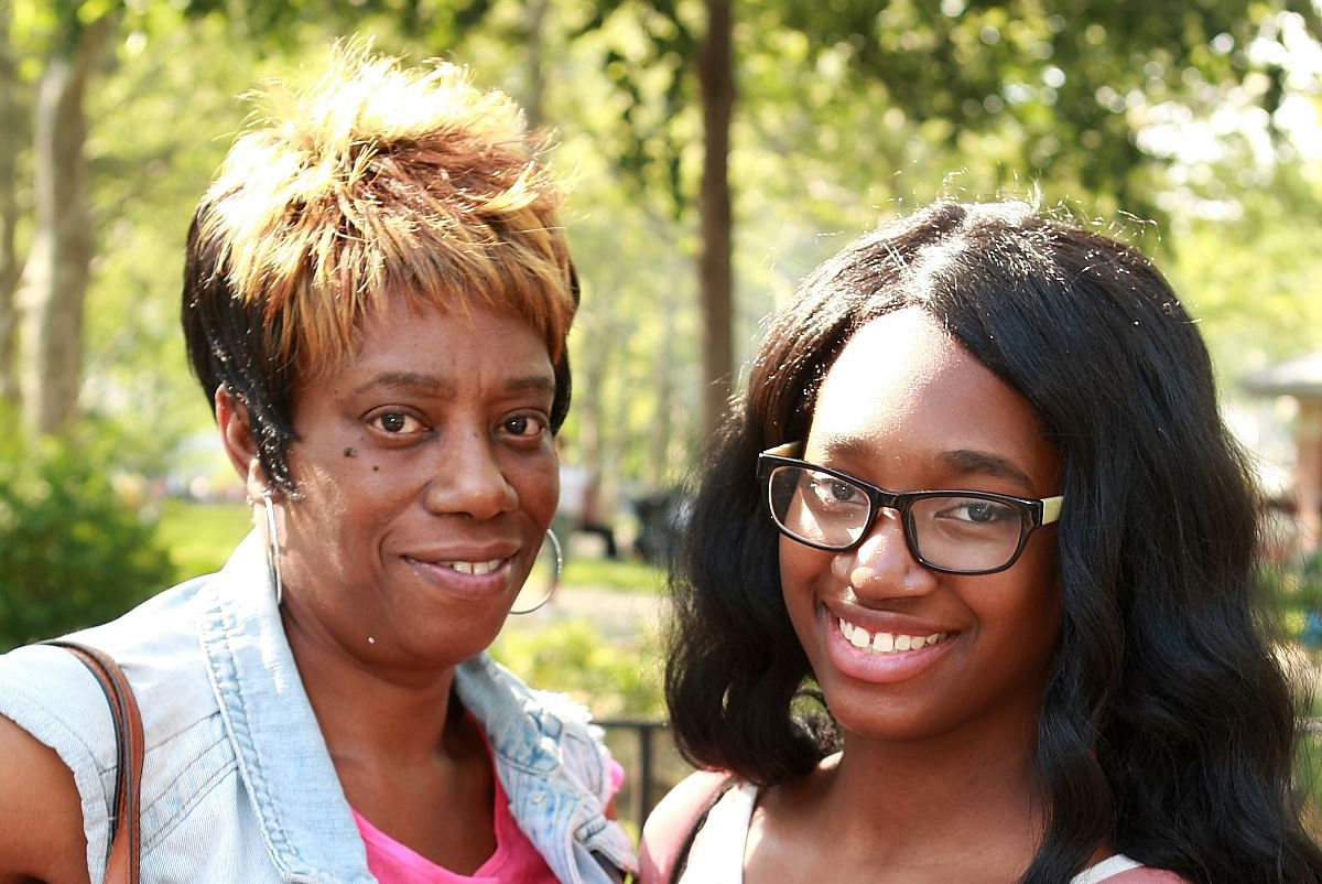 two women smiling and posing for a photo on a sunny day