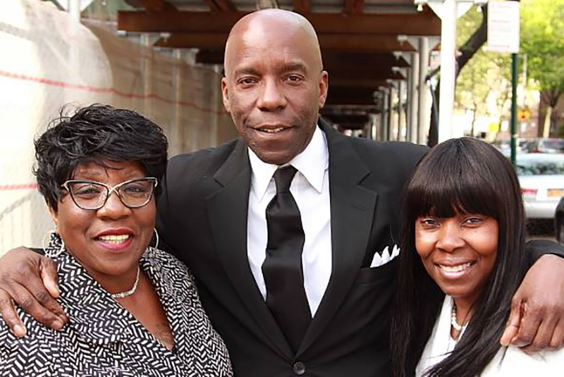 man in suit, one woman wearing glasses and another woman posing for a photo