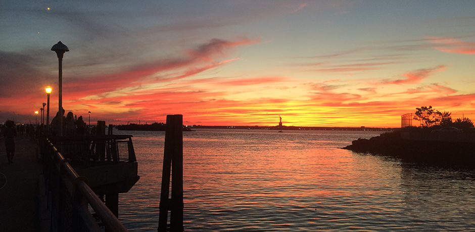 New York Harbor during sunset and a public pier in foreground
                                           