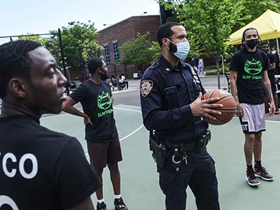 Photo of a police officer playing basketball with local kids