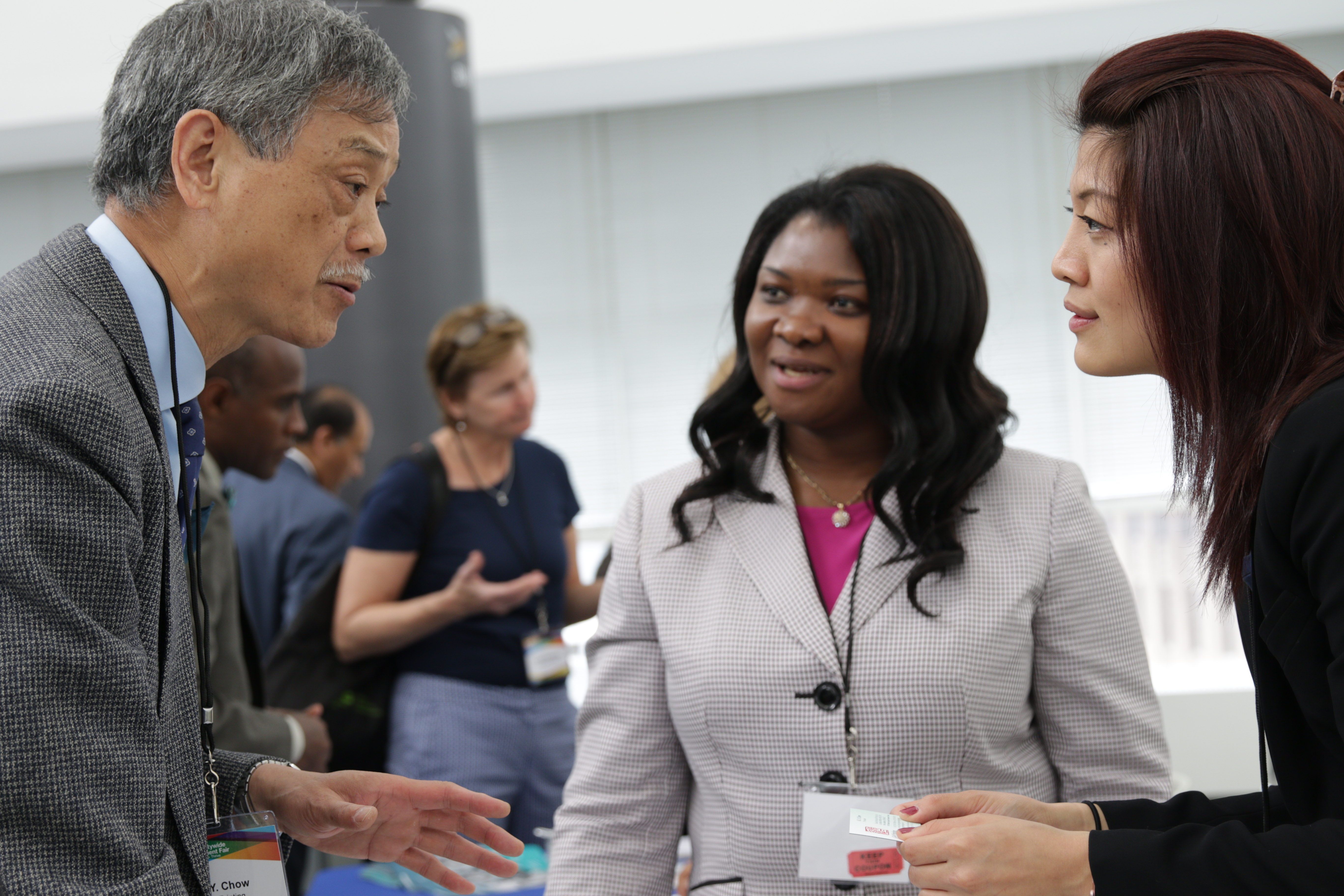 An Asian man, Asian woman, and black woman are in a discussion at the Annual Citywide Procurement Fair