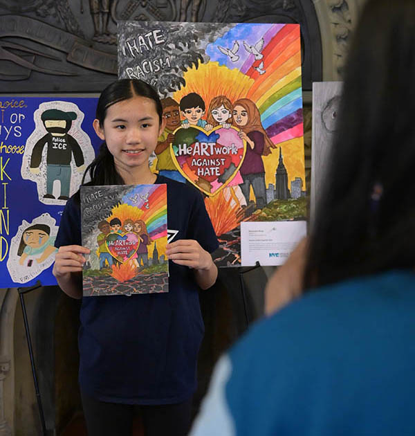 A young girl smiles while holding her art