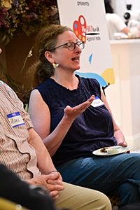 A lady is speaking holding her plate at BBBB.