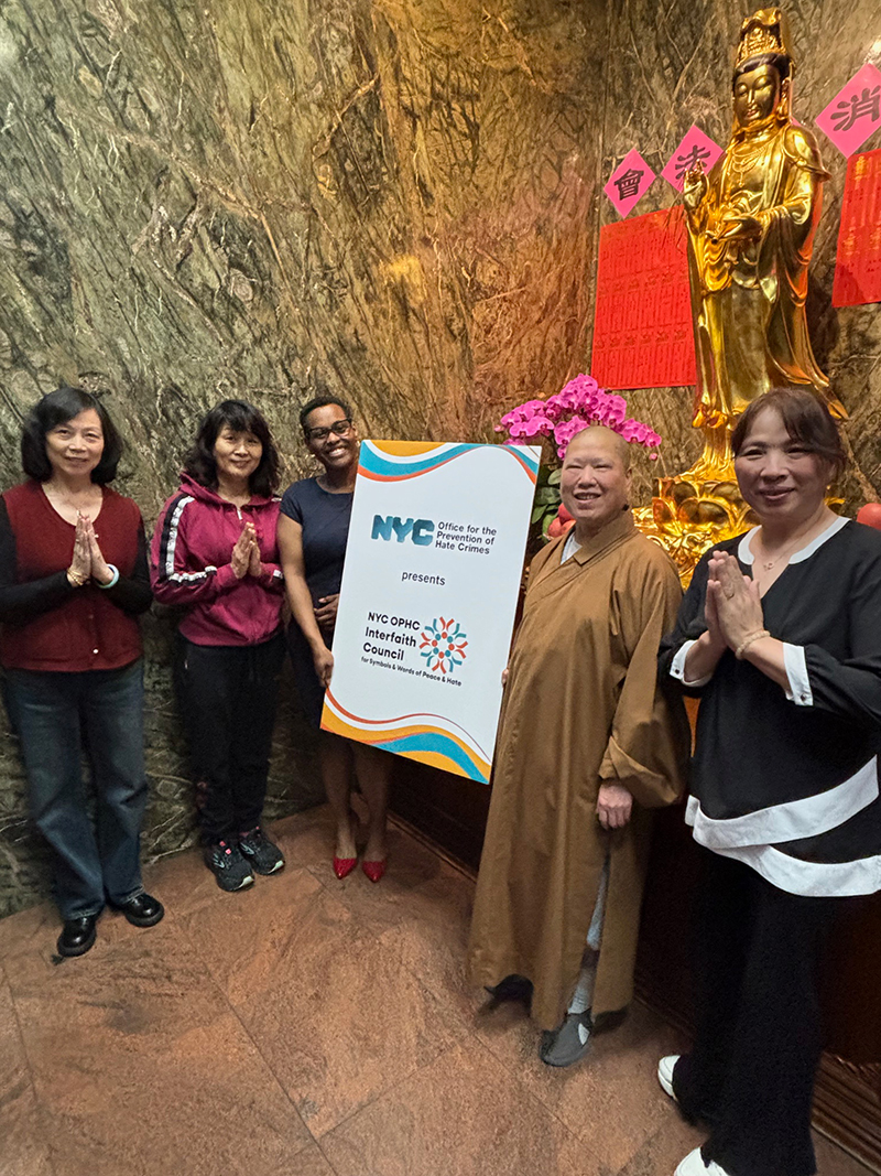 A Buddhist nun and follower stood next to Interfaith Council's sign with smiles