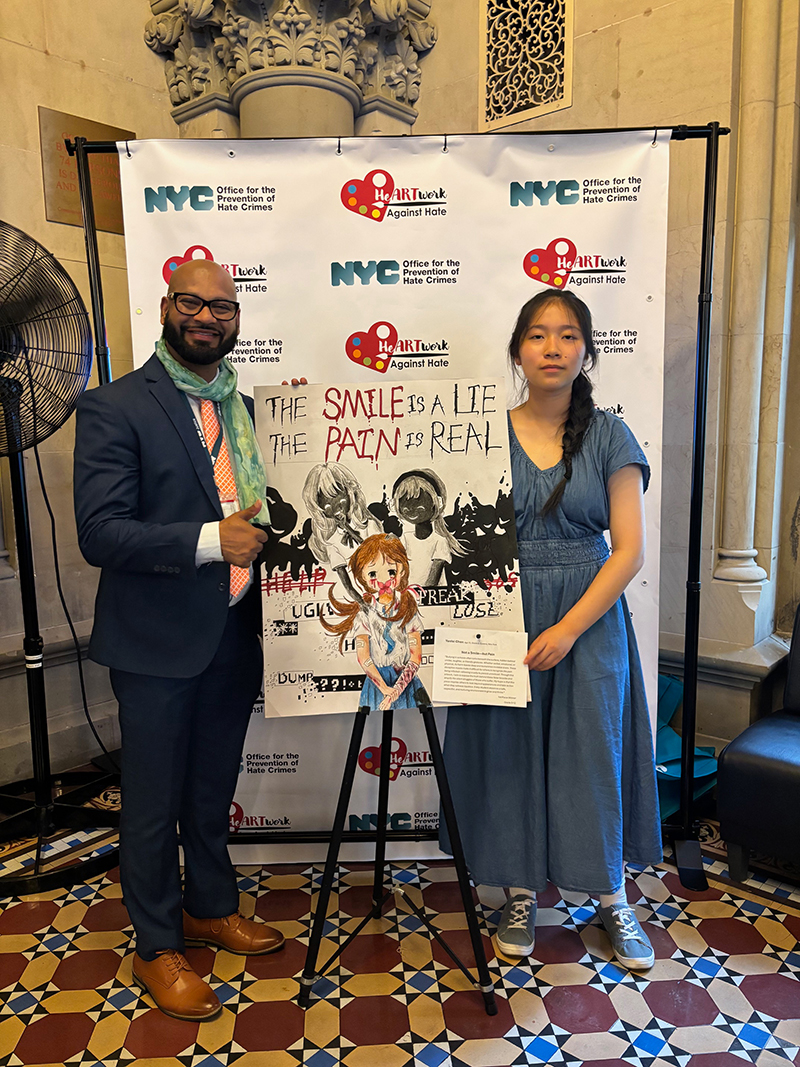 OPHC Executive Director Vijah Ramjattan stands with a high school student winner with her artwork