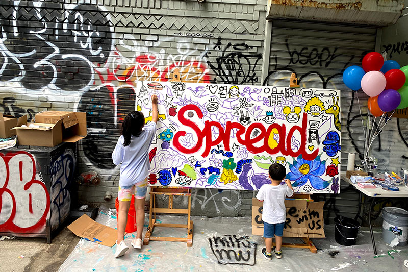 two kids painting a large canvas