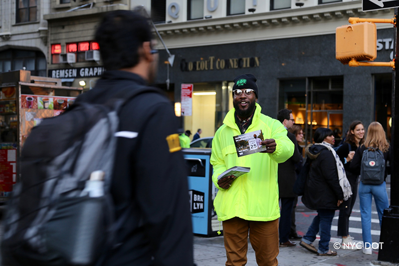 Man in a yellow jacket handing out flyers