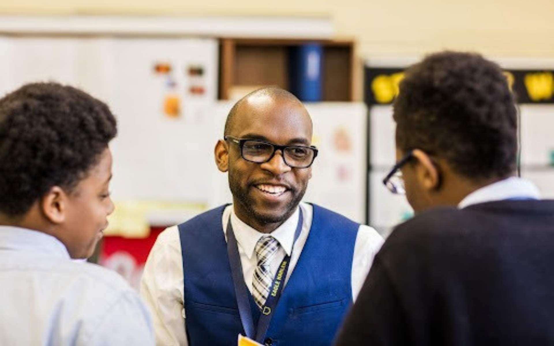 Male teacher of color with students.
                                           