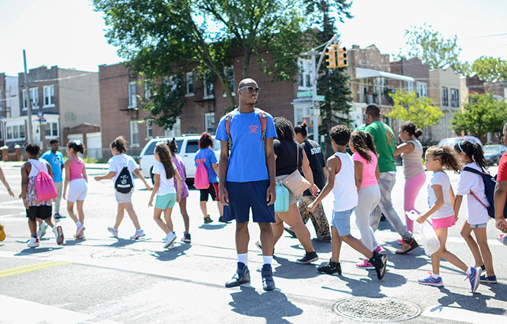Children crossing street behind camp counselor
                                           