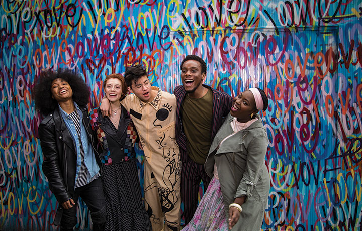 Group of people standing in front of wall, laughing
                                           