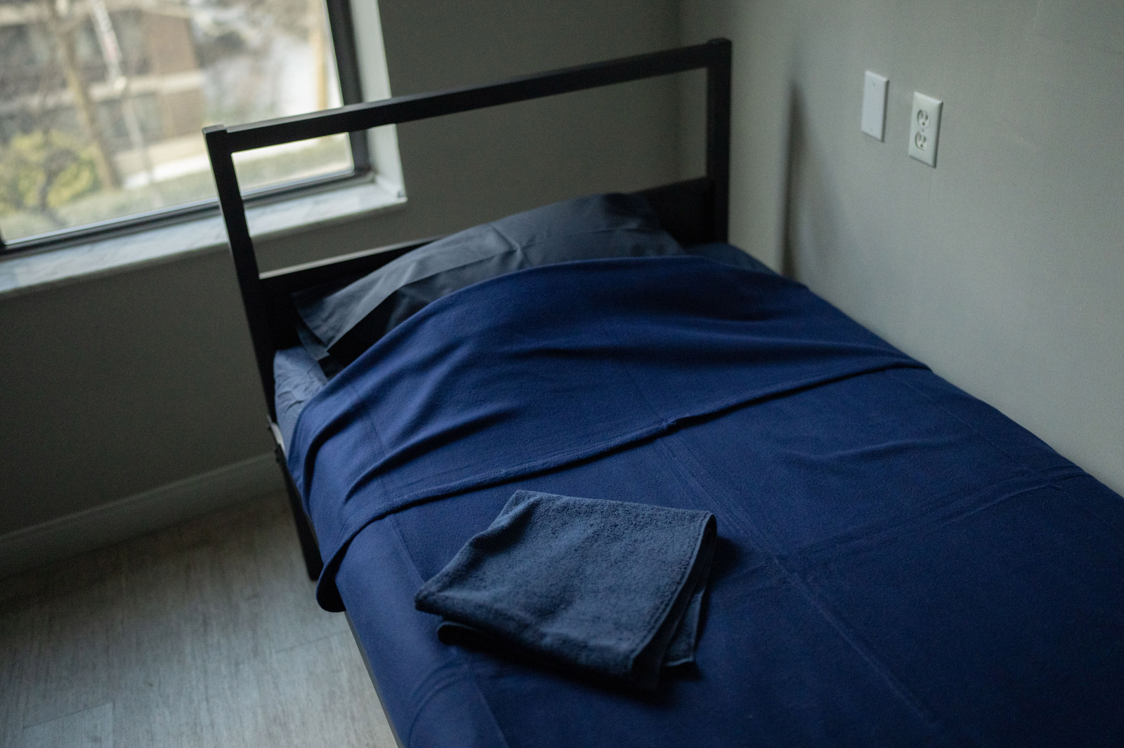 a bed covered a sheet of blanket in navy in a room.