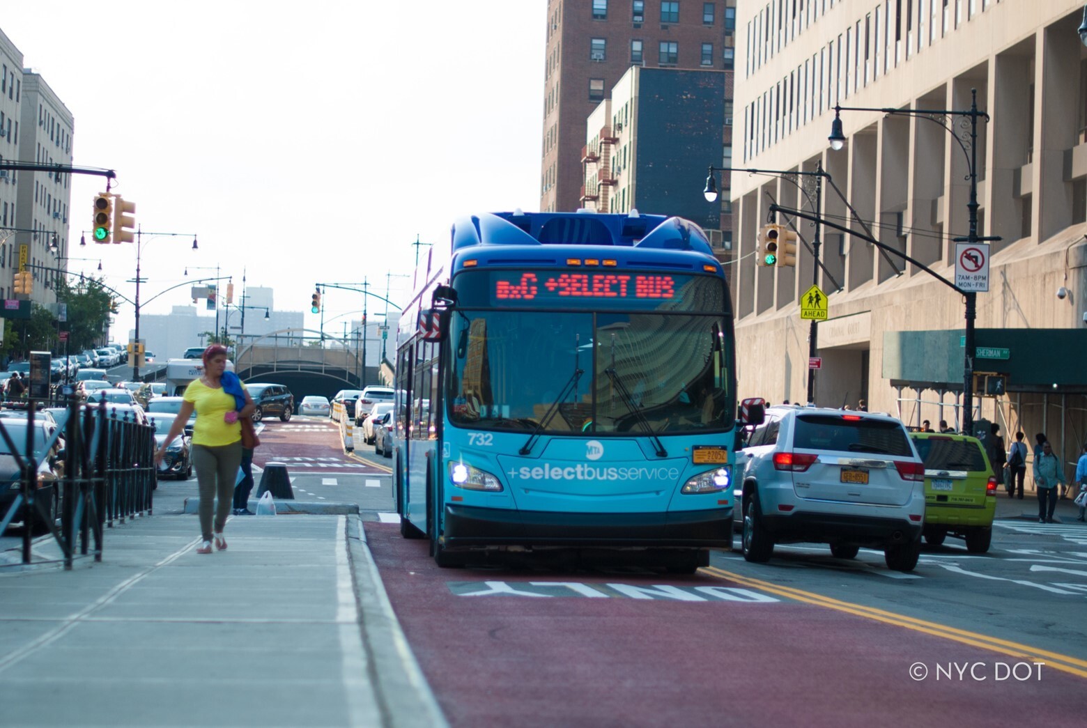 A bus is moving toward the frame, while a person walking  on sidewalk