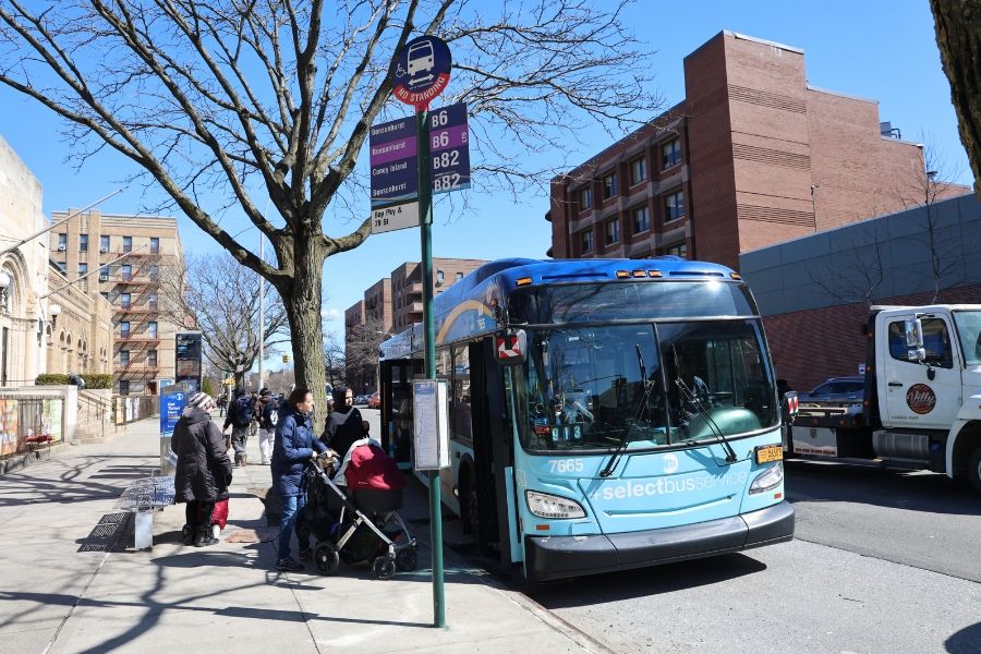 An M T A bus picks up passengers at a bus stop on Bay Parkway.
