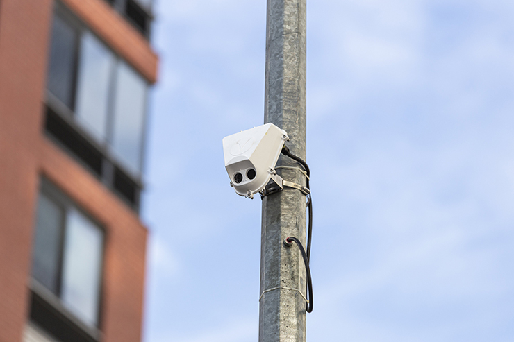 A small gray box is attached to a street light pole.