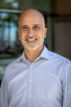 Portrait of N Y C D O T Chief Technology Office Julio Useche. He is wearing a light blue button-down shirt and smiling at the camera.
